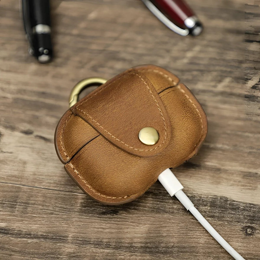 Stylish leather airpod case with brass accent, perfect for protecting your earbuds in style.